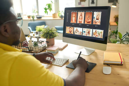 Photo editor working on desktop computer at office desk retouching photo with image editing softwareの写真素材