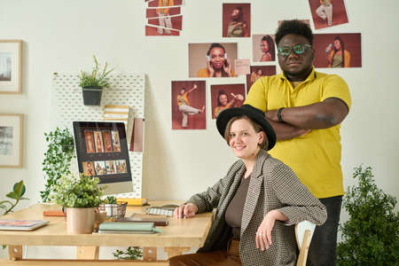 Portrait of African editor and retoucher looking at camera while working in team on computer at officeの写真素材