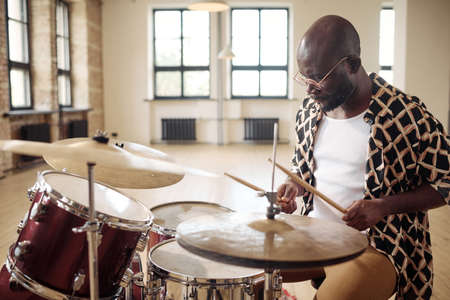 African young man drummer behind drum set playing the drums in studioの写真素材