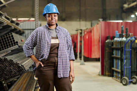 Portrait of African professional heavy industry worker in helmet standing in workshop of factoryの写真素材