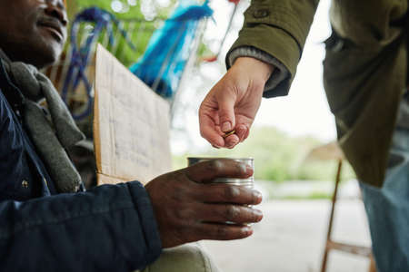 Close-up of man giving money to homeless man while he begging outdoors in the cityの写真素材