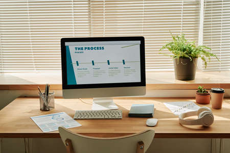 Horizontal image of workplace of business person with computer monitor on it and program on screen at modern officeの写真素材