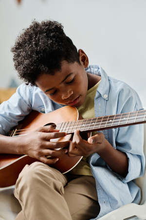 African boy examining the notes on guitar while he learning to play musical instrument at lessonの写真素材