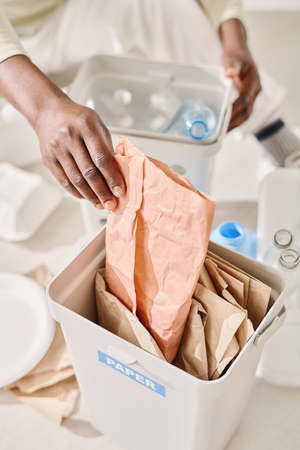 Close-up of African man sorting plastic and paper in containers for recyclingの写真素材
