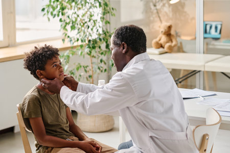 African pediatrician examining sore throat of little patient during medical exam at officeの写真素材