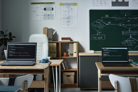 Horizontal image of modern empty class with computers with coding on monitors for IT lessonの写真素材