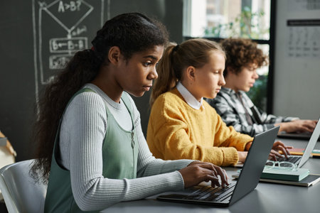 Group of children sitting at desk in a row and working with new software on computers at classの写真素材