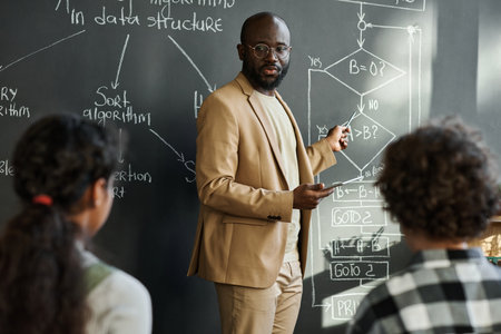 African American teacher explaining formula on blackboard to children during IT technology lessonの写真素材