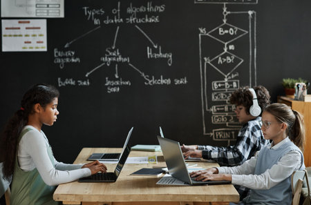 Group of children learning to work with computer program at table during IT technology lessonの写真素材