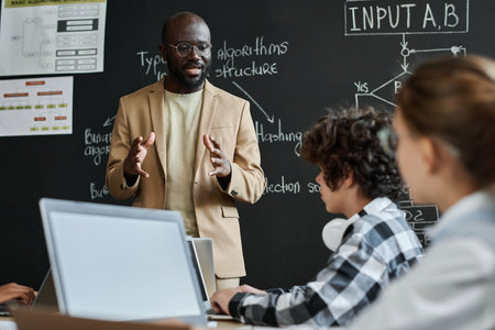 African American teacher explaining the work of computer system to children during IT technology lessonの写真素材
