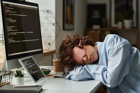IT developer in mask sleeping at her workplace after hard work with software on computer