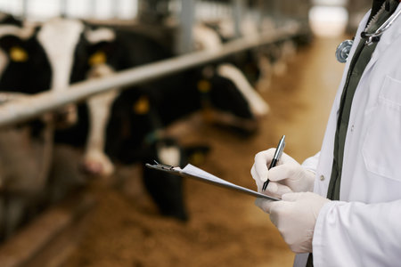 Close-up of vet doctor in uniform writing prescription in medical card during his work on farmの写真素材