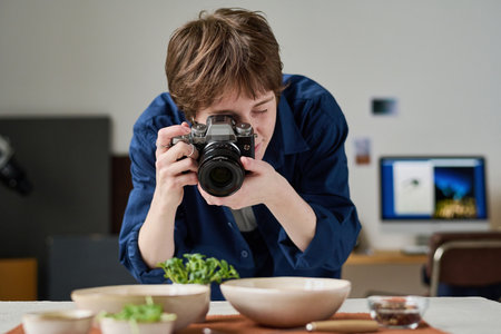 Female photographer using digital camera to take picture of food during her work in studio