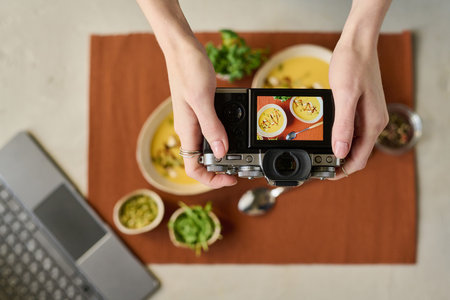 High angle view of young photographer shooting still life portrait of soup in bowlsの写真素材