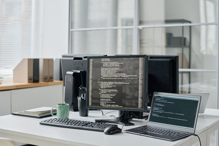 Horizontal image of workplace of programmer with computer monitors with codes on screens standing on...
