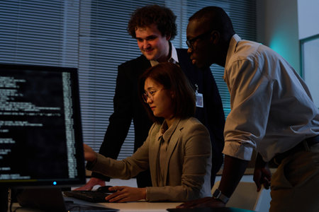 Group of programmers working with security codes together till late evening in IT officeの写真素材