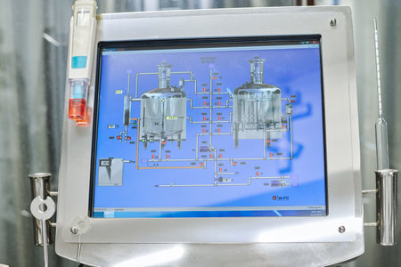 Close-up of computer monitor with tanks and tubes on the screen for controlling process of brewing in plantの写真素材