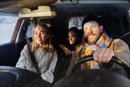 Happy family sitting in car with their child while dad driving, they travelling during winter...
