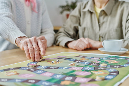 Close-up of senior woman making a move on the map, she playing board game with her friend at tableの写真素材