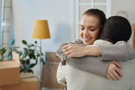 Happy multiethnic couple embracing each other holding keys, they moving to their new apartmentの写真素材