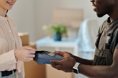 Close-up of young woman paying for service with credit card for moving