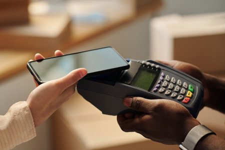 High angle view of young woman holding smartphone to pay for service online