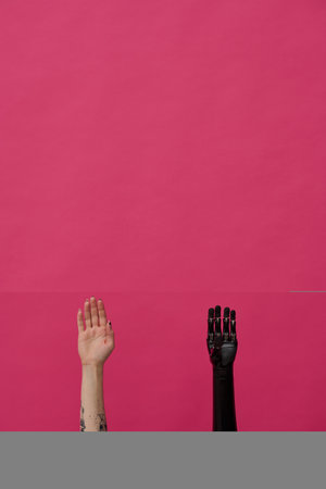 Close-up of girl with healthy hand and prosthetic hand against pink backgroundの写真素材