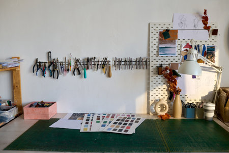 Part of workshop of tanner with sample swatches, box with leather pieces and other supplies on table...