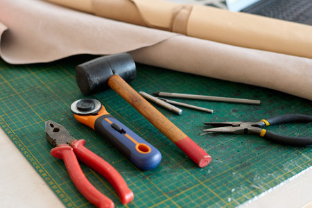 Group of handtools necessary for tanner work and rolled paper for sketching new item models on table of leather workerの写真素材