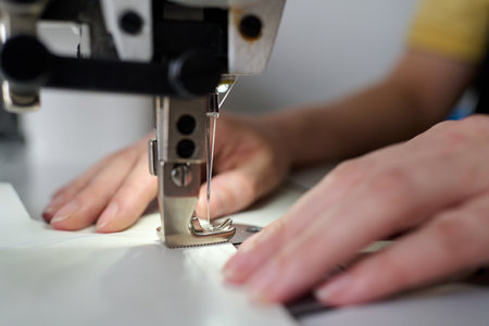 Selective focus on small steel or metallic detail of electric sewing machine and needle with thin...