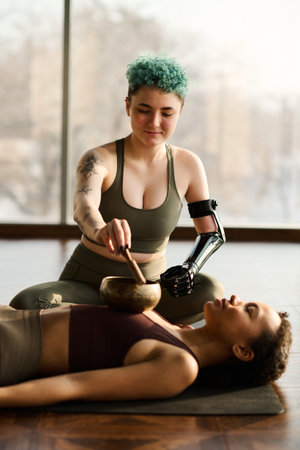Young girl relaxing during yoga while instructor using singing bowlの写真素材
