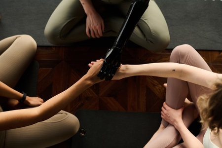 High angle view of group of young girls holding hands while sitting on exercise mat during training in gymの写真素材