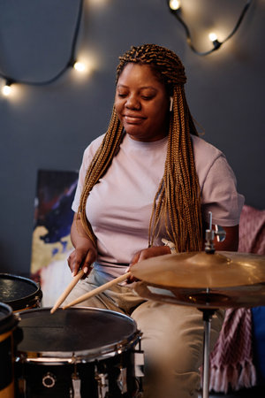 Vertical image of African American drummer playing drums in studio during repetitionの写真素材