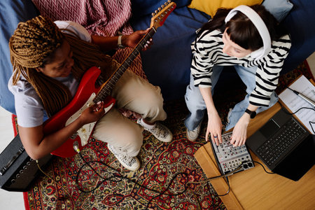 High angle view of young women playing guitar while writing music together in studioの写真素材