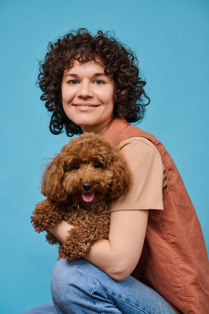 Vertical portrait of happy owner posing with her pet against blue backgroundの写真素材