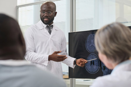 African American doctor in white coat giving educational information to his colleagues pointing at monitor during conferenceの写真素材