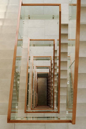 Vertical image of modern staircase with glass railing in high office buildingの写真素材