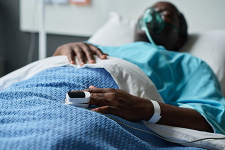 African American senior man with oxygen mask lying on bed in hospital wardの写真素材