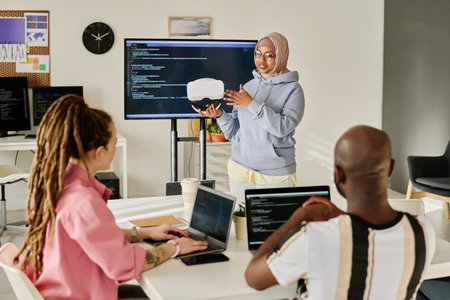 Young woman presenting new VR glasses to her colleagues during meeting in officeの写真素材