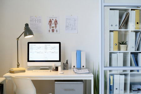 Modern office of doctor with workplace with computer on table and posters on the wallの写真素材