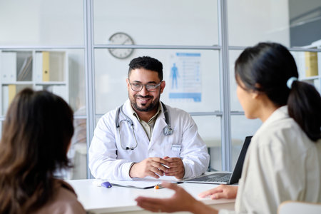 Smiling pediatrician talking to parent and child during their visit to clinic