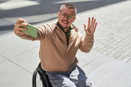 Young man with disability having video call on his smartphone during his walk in the city