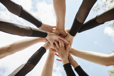 Low angle view of people from cheerleader team holding hands and supporting each other before performanceの写真素材