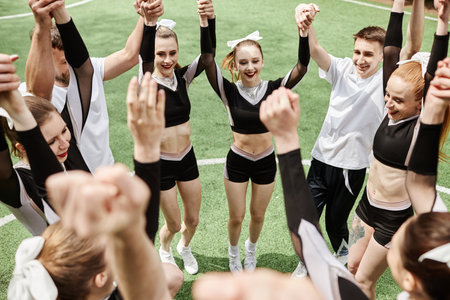 Cheerleader team holding hands while standing outdoors, they happy with victory in competitionの写真素材