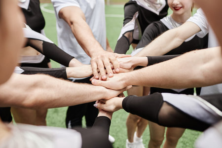 Close-up of cheerleaders and their coach holding hands together to support each other before competitionの写真素材