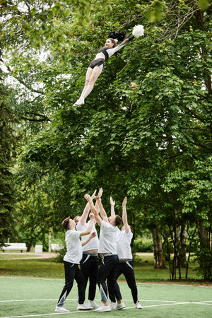Vertical image of cheerleader team doing tricks outdoors during performanceの写真素材