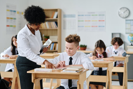 African American teacher talking to schoolboy during lesson at schoolの写真素材