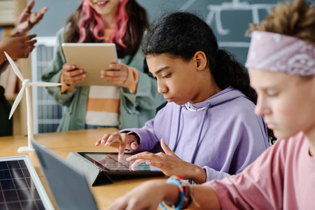 Schoolgirl using gadgets during lesson together with her classmatesの写真素材