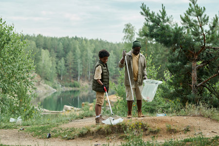 Family of two cleaning the environment of forest together, they picking up garbage in bagsの写真素材