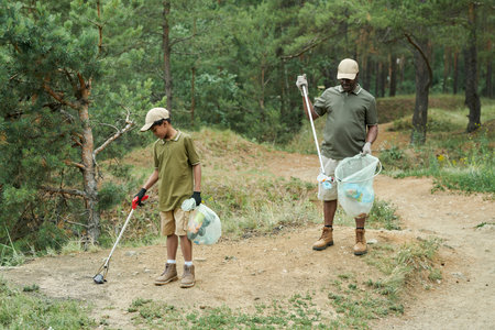 Volunteers cleaning forest from garbage together in summer dayの写真素材